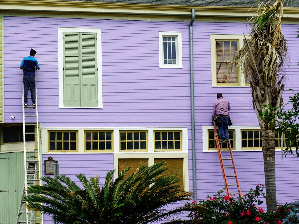 Painter on a ladder preparing an exterior wall